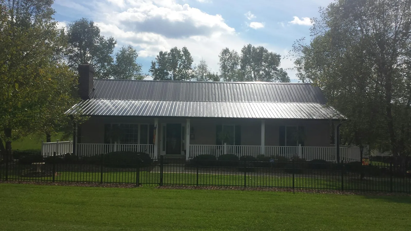 Gray metal roof on a brick ranch with a full width front porch — Gutter Guard Installation work by our crew in Eudora