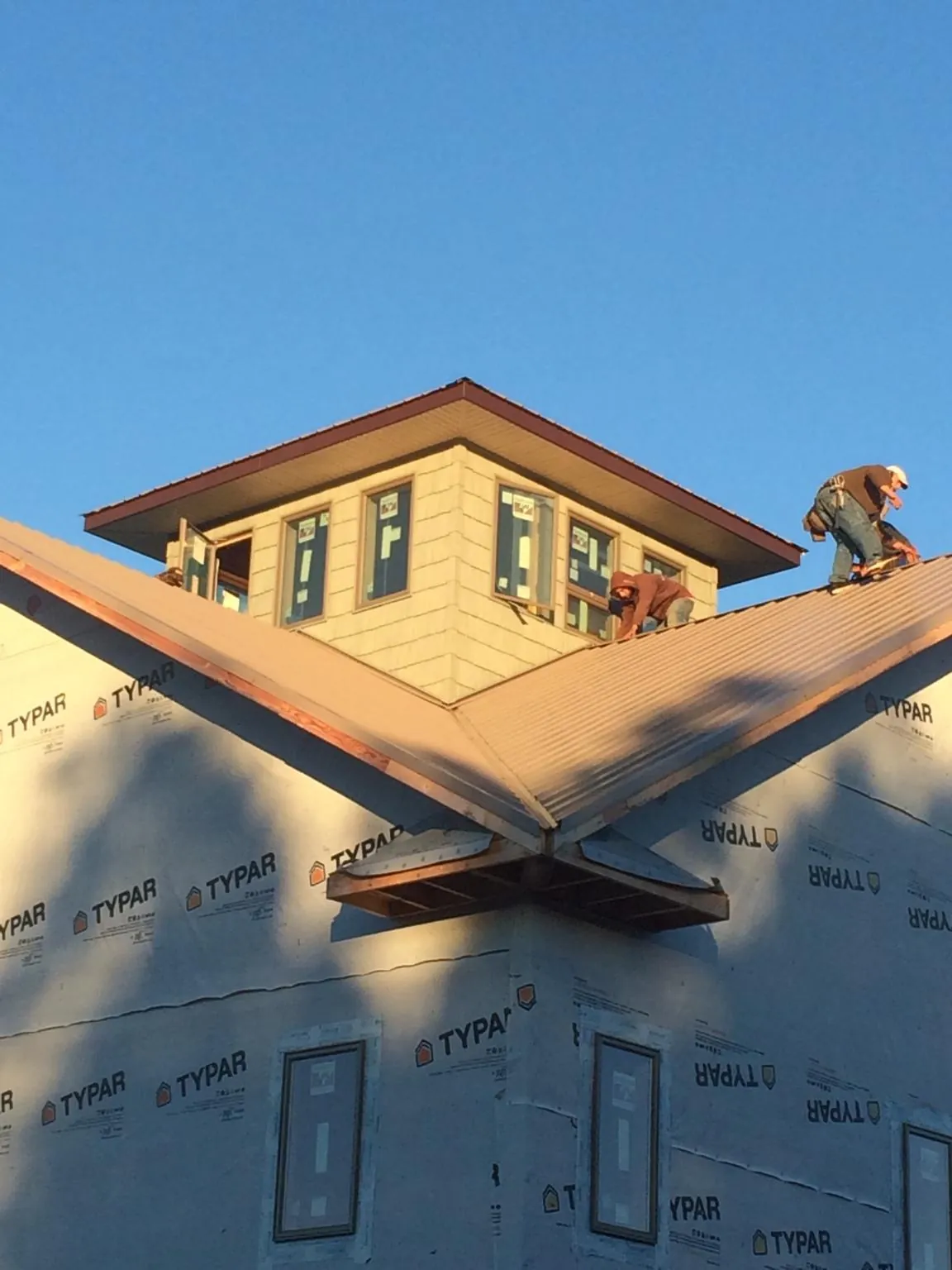 Roofers working around a rooftop cupola on a new metal roof at sunset — Roof Waterproofing in Eudora by Roofing Brothers